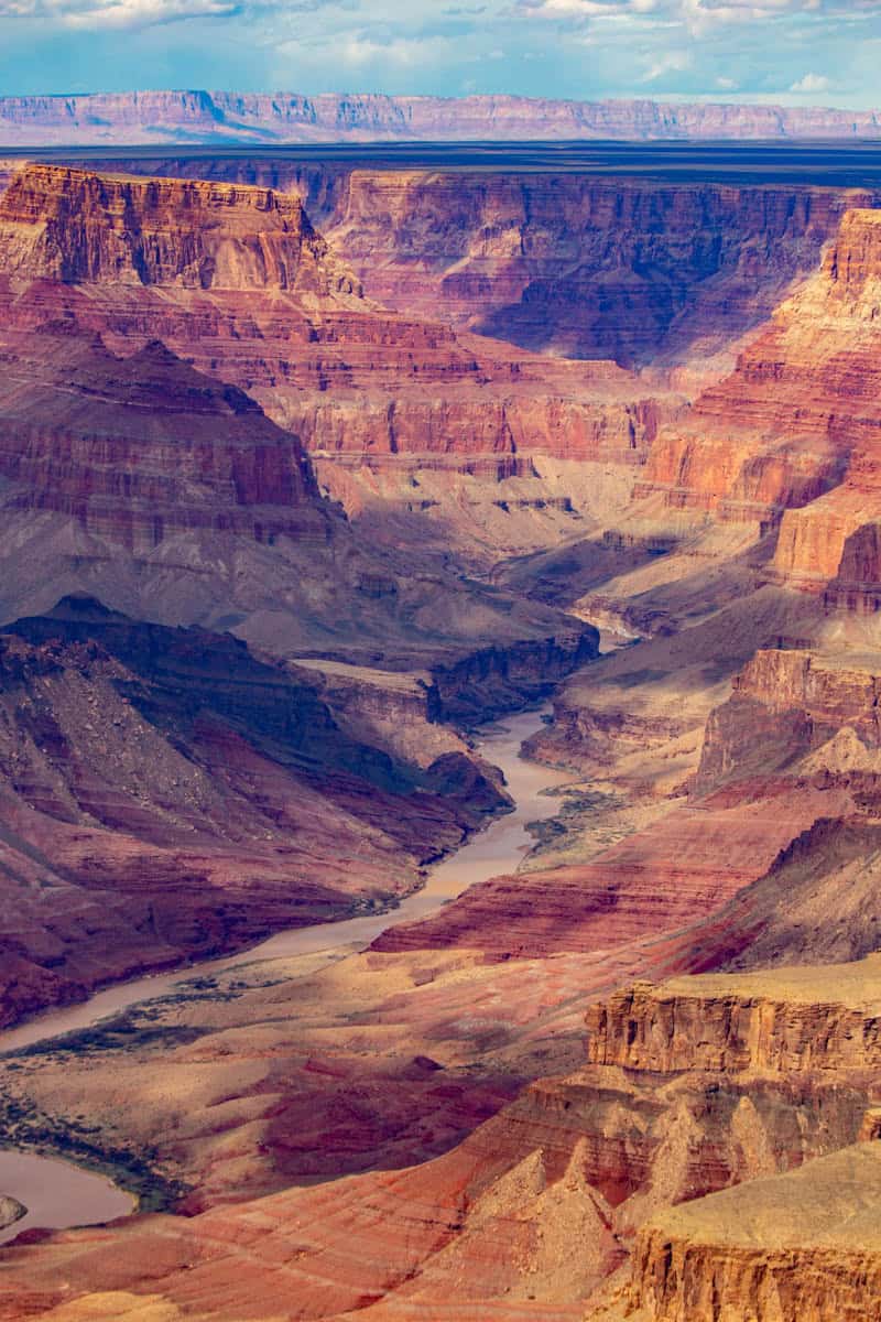 A tall sequence of cliffs follows the muddy Colorado River through steep, multicolored canyon walls in Grand Canyon National Park, Arizona, United States, with Terraced rock layers nearby.