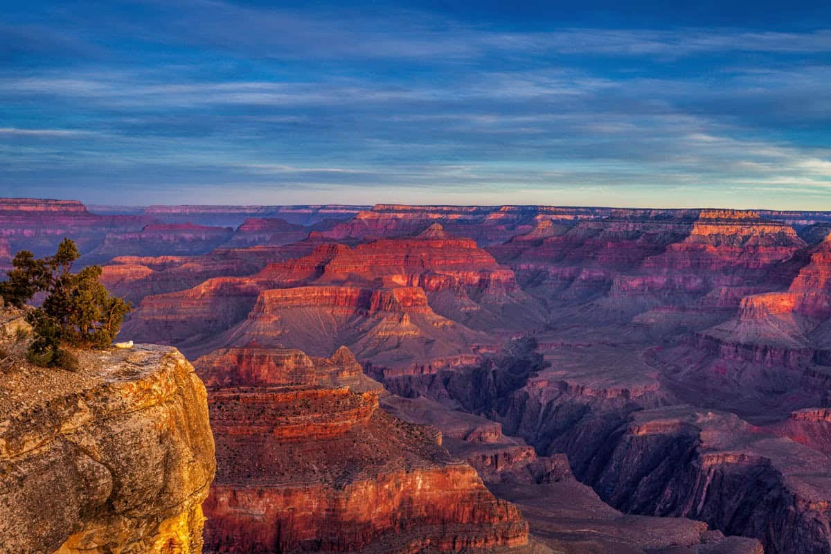 Red canyon terraces glowing beneath evening clouds in Grand Canyon National Park, with Inner gorge visible.