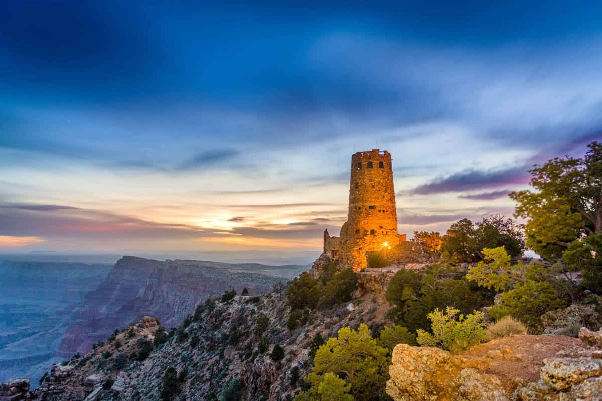 Historic stone watchtower rising above the rim in Grand Canyon National Park, with Rocky rim visible.